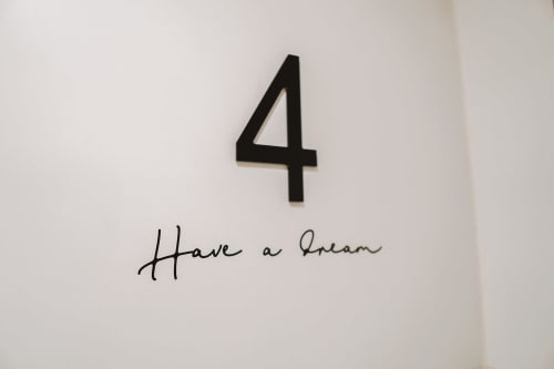 Número 4 negro con texto 'Have a Dream' en pared blanca del Hotel Boutique Mamma Mia Tossa