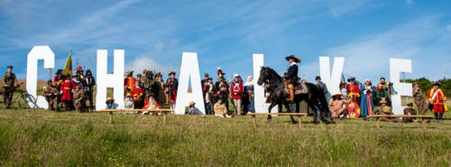 Historical reenactment group in period costume at Glebe House, Salisbury, with large white letters backdrop