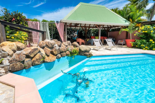 Bright blue swimming pool with rock features at Gites villa Bagatelle in Sainte-Rose, Guadeloupe, featuring loungers and