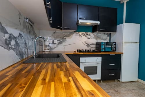Cuisine moderne aux Gites villa Bagatelle à Sainte-Rose : comptoir bois, armoires noires, dosseret marbre et turquoise