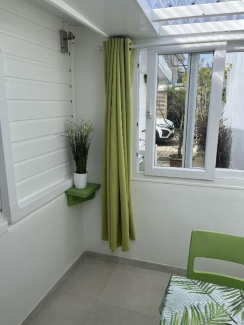 Chambre moderne à la Résidence B&L Lagon : murs blancs, accents verts, portes-fenêtres coulissantes et vue sur le jardin