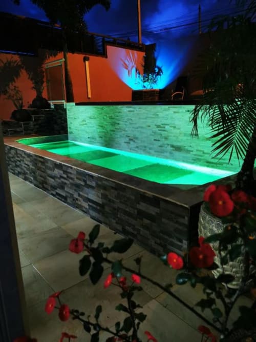Piscine illuminée aux LED vertes à la Résidence B&L Lagon, bungalow en Martinique, entourée de plantes tropicales