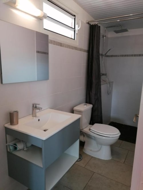 Salle de bain moderne du Bungalow Corail à la Résidence B&L Lagon avec lavabo, toilettes, douche et miroir