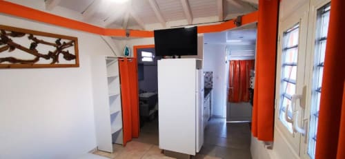 Intérieur contemporain du bungalow à la Résidence B&L Lagon avec accents orange, kitchenette et vue sur jardin en Martinique