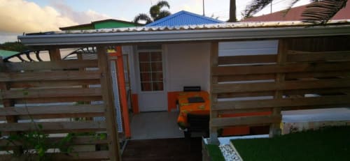 Vue jardin du Bungalow Corail à la Résidence B&L Lagon, Martinique - terrasse en bois avec chaises orange et toit bleu