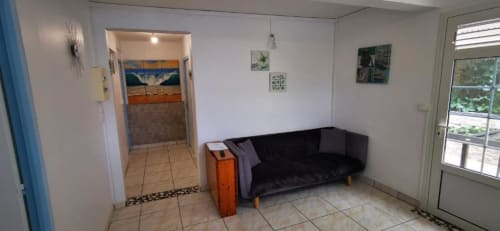 Séjour de l'appartement deux chambres Alisée à la Résidence B&L Lagon à Sainte-Luce : canapé noir, portes donnant sur le jardin, carrelage