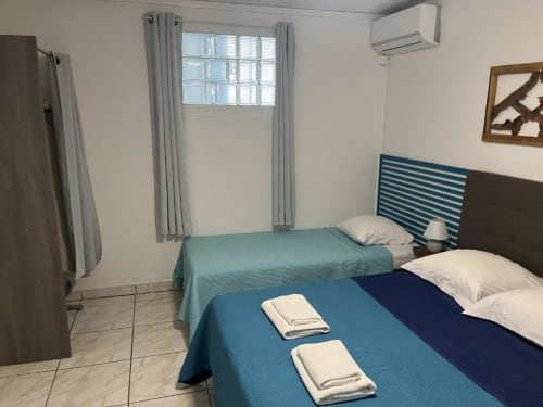 Deux lits dans une chambre lumineuse à la Résidence B&L Lagon, Sainte-Luce avec fenêtre, climatisation et vue sur le jardin
