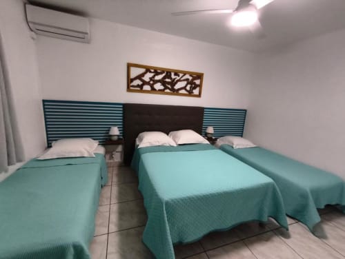 Chambre twin lumineuse à la Résidence B&L Lagon à Sainte-Luce avec literie turquoise, tête de lit sombre et décor moderne