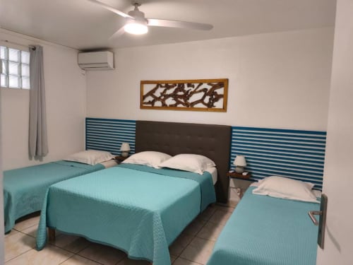 Appartement lumineux 2 chambres à la Résidence B&L Lagon à Sainte-Luce avec lits turquoise, têtes de lit rayées et vue sur le jardin