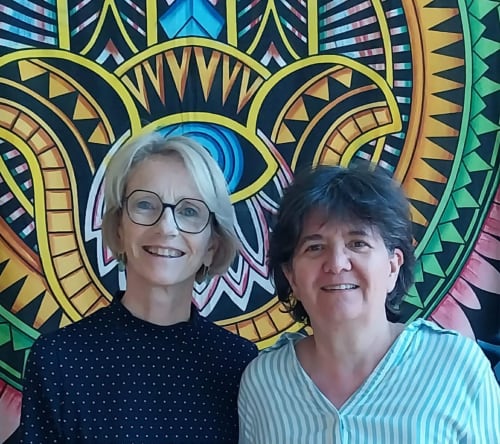 Deux hôtes souriants au Domaine de Londeix en Dordogne, avec un fond de mandala coloré