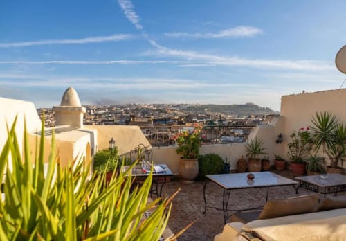 Terrasse sur le toit de l'hôtel Le Cèdre d'Argent à Fès avec plantes en pots, espaces de détente et vue sur la médina