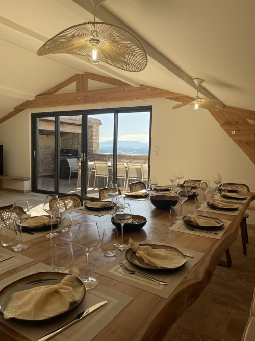Élégante salle à manger du Domaine Maison Girardon avec vue sur les montagnes, poutres en bois et tables dressées