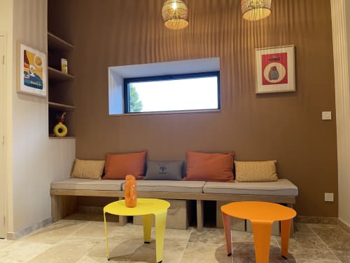 Petit coin salon douillet avec banquette intégrée beige, coussins orange, tables d'appoint jaune et orange au Domaine Maison Girardon