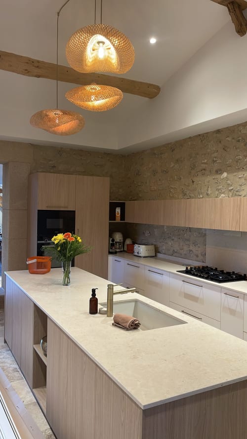 Cuisine moderne avec îlot, mobilier blanc et trois luminaires suspendus en osier à Domaine Maison Girardon, La Roche