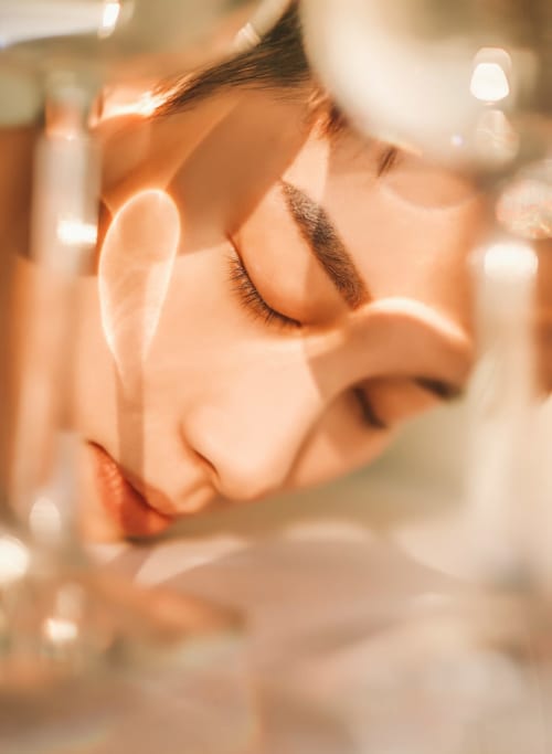 Femme aux yeux fermés et sourcils noirs à l'hôtel Le Cèdre d'Argent à Fès, entourée par la lumière douce des chandelles