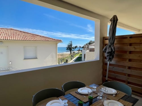 Balcon d'appartement face mer à Marina di Bravone avec vue panoramique, coin repas, écran de confidentialité et paysage côtier
