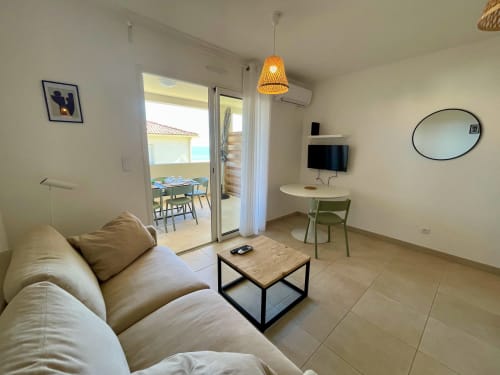 Modern sea-view apartment living room at Marina di Bravone with sofa, TV, desk, and beach access balcony