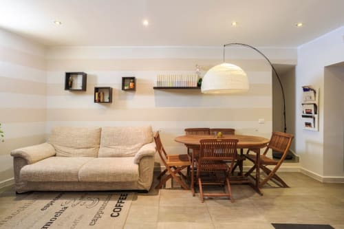 Zona living moderna a Marilù B&B Palermo con divano beige, tavolo in legno, lampada ad arco e pareti decorate a righe