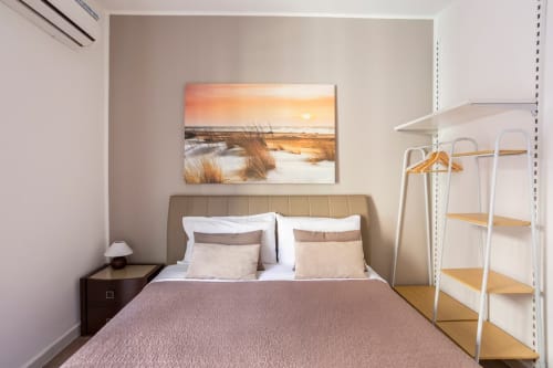 Camera matrimoniale moderna a Marilù B&B Palermo con testata beige, scaffali bianchi, arte marina al tramonto e vista città