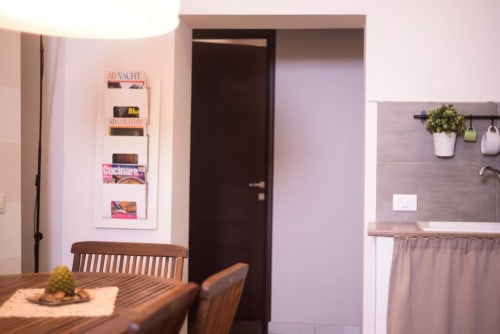 Zona living e cucina moderna nella camera di Marilù BnB Palermo con tavolo in legno, porta marrone e angolo cottura con piante sospese