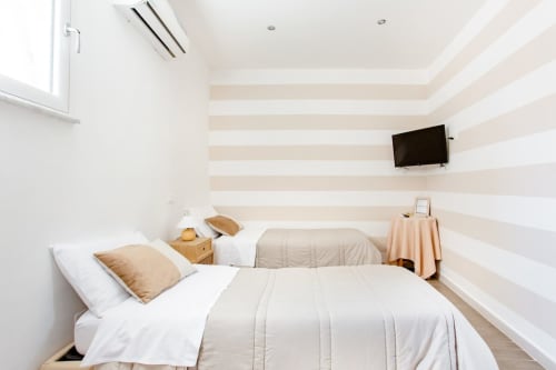 Camera matrimoniale moderna a Marilù B&B a Palermo con letti gemelli, parete a righe, TV schermo piatto e design minimalista