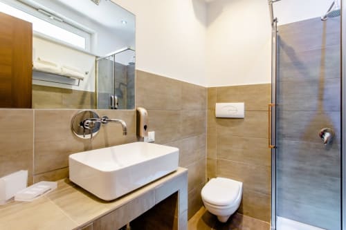 Bagno moderno del Marilù B&B a Palermo con lavabo bianco a parete, rubinetto murale, piastrelle, toilet e doccia in vetro