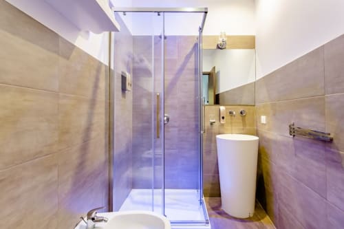 Bagno moderno al Marilù B&B di Palermo con doccia in vetro, lavabo bianco e piastrelle beige