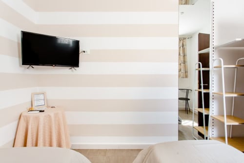 Camera matrimoniale moderna con pareti rigate, TV a schermo piatto e scaffali bianchi al Marilù B&B di Palermo