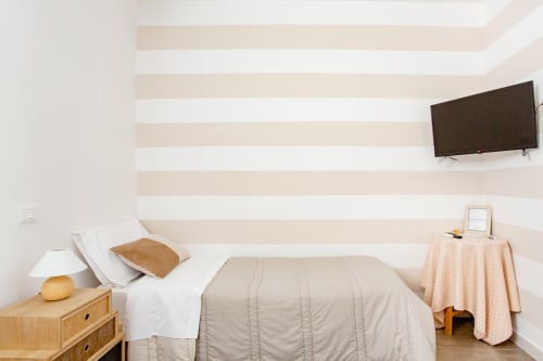 Camera doppia moderna a Marilù B&B a Palermo con parete a righe, letti gemelli, comodino in legno e TV a muro
