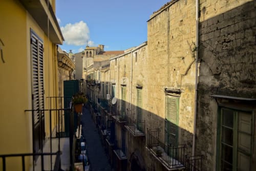 Stretto vicolo lastricato a Palermo con edifici storici in pietra e persiane gialle, corte interna della struttura Marilù