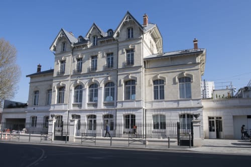 Gare Godillot, une demeure historique de style mansardé accueillant des hôtes à Saint-Ouen-sur-Seine, avec toit mansardé et fenêtres en arc.