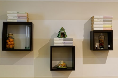 Esposizione scaffali Marilù B&B Palermo con libri, statuette decorative a cupola e bottiglie in vetro ambra