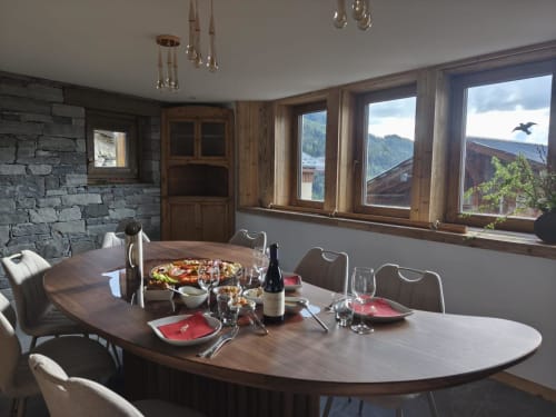 Élégante salle à manger de L'Alp'In avec vue montagne, table dressée, cheminée en pierre et mobilier en bois à La Plagne