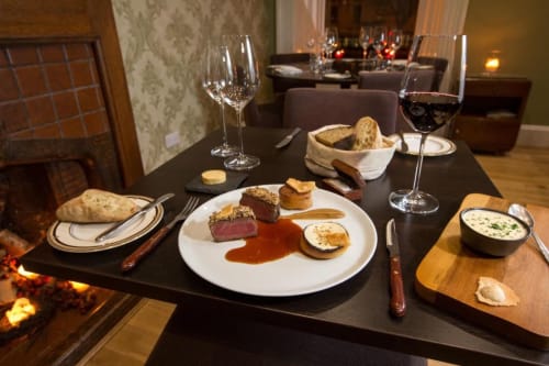 Fine dining table setting at The Ford Apartment Perth with plated beef, wine glasses, and bread service
