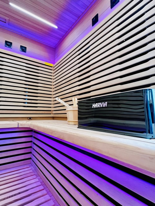 Intérieur de sauna moderne du gîte Vivre l'Instant à Amboise avec éclairage violet et bancs en bois à rayures noires
