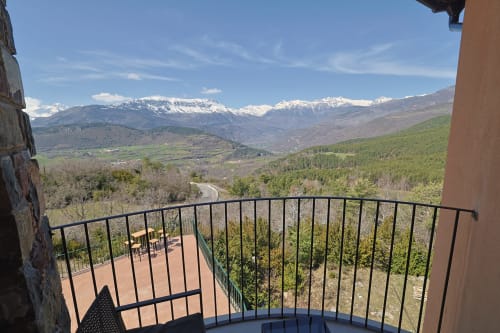 Hotel Fonsispa balcony overlooking snow-capped mountains, forested valley, and winding road in Renanué, Spain