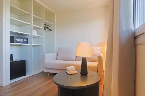 Modern hotel room at Hotel Fonsispa in Renanué with beige sofa, round black table, and built-in shelving