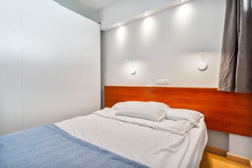 Modernes Schlafzimmer mit orangefarbenem Holzkopfteil, weißen Kissen und blauer Bettwäsche in der M&M Suite des Home Stay Gran Canaria, Maspalomas