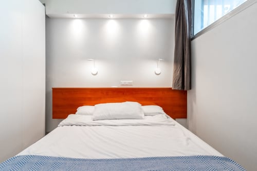 Modernes Schlafzimmer mit orangefarbenem Holzkopfteil, weißer Bettwäsche und Einbauleuchten in der M&M Suite des Home Stay Gran