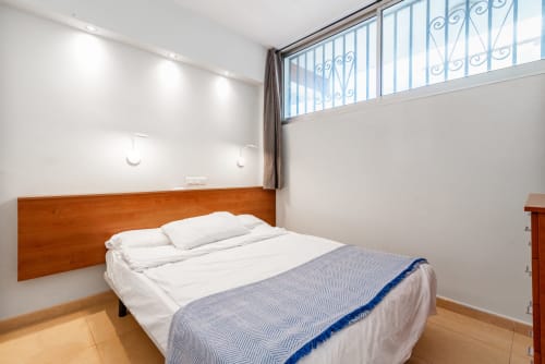 Helles modernes Schlafzimmer mit Holzbettgestell, weißer Bettwäsche und blauer Wurfdecke in Apartment in Maspalomas