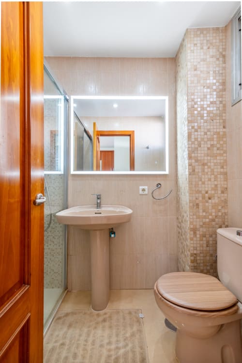 Modernes Badezimmer in der M&M Suite des Home Stay Gran Canaria, Maspalomas, mit Pedestal-Waschbecken, beleuchtetem Spiegel und gefliester Dusche