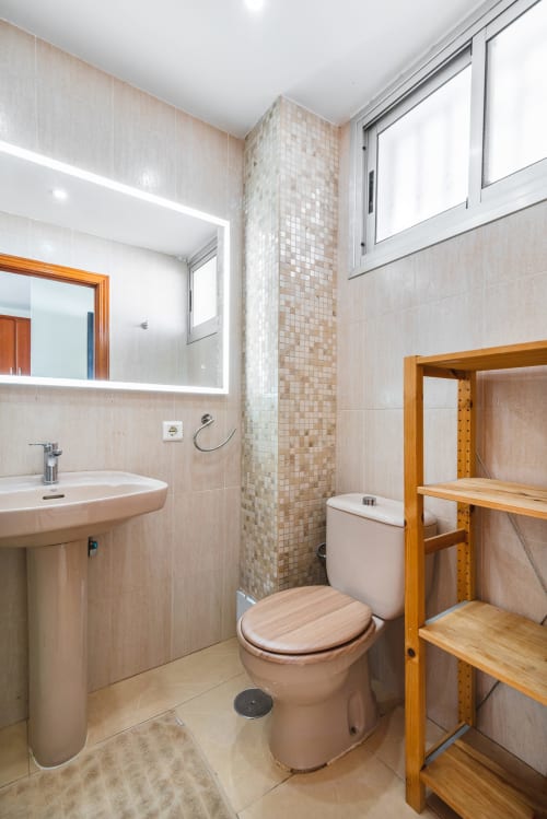 Modernes Badezimmer in der M&M Suite von HomeStayGranCanaria, Maspalomas, mit beigen Fliesen, Holzregalen und Waschtisch