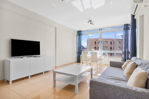 Modernes Wohnzimmer in Maspalomas mit Sofa, Fernseher, Essbereich und Balkonblick auf Pool und Umgebung