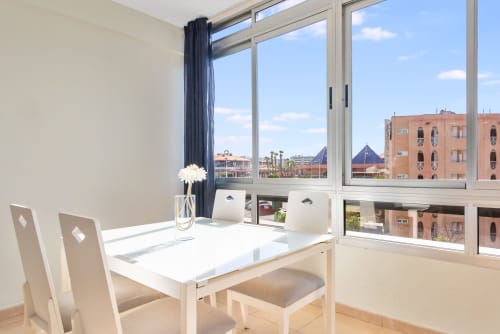 Modernes Esszimmer mit weißem Tisch und Stühlen mit Blick auf Maspalomas, Gran Canaria von einem Hochhaus-Balkon