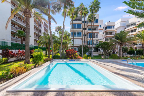 Schwimmbad mit Bahnmarkierungen im Home Stay Gran Canaria in Maspalomas, umgeben von Palmen und modernen Apartments