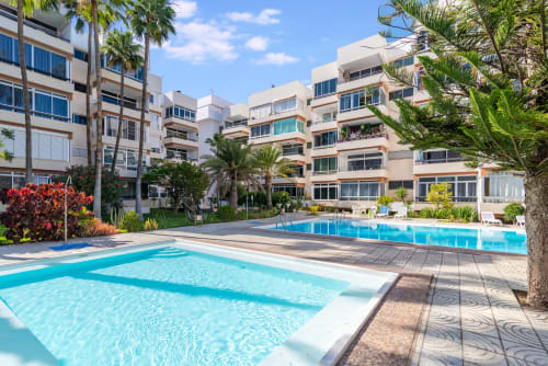 Apartmentanlage Maspalomas mit türkisfarbenen Pools, Palmen und modernen beigefarbenen Gebäuden unter klarem blauen Himmel