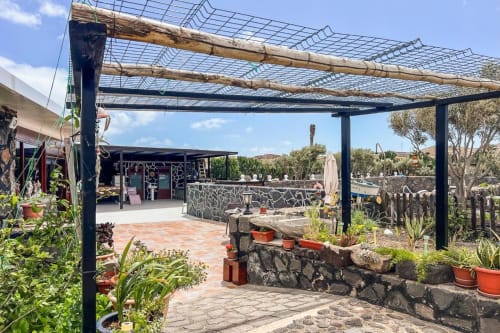 Terraza exterior de Finca Villanueva en Mala con pérgola, muros de piedra, plantas en macetas y vistas a la montaña