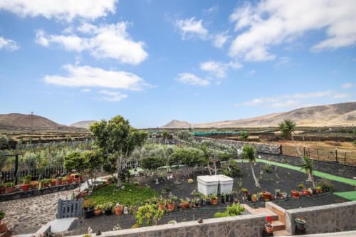 Jardín Finca Villanueva en Mala con paisaje volcánico, macetas, bancales escalonados y vistas montañosas bajo cielo azul