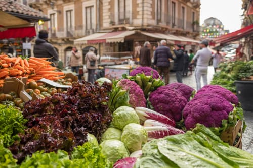 Vivace mercato palermitano con cavolfiore viola, lattuga e carote freschissime esposte nei banchi dei venditori