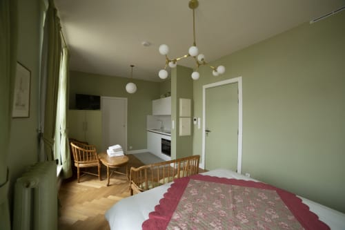 Studio 301 à Gare Godillot, Saint-Ouen : chambre vert sage avec cuisine, mobilier en bois, luminaires suspendus et moderne
